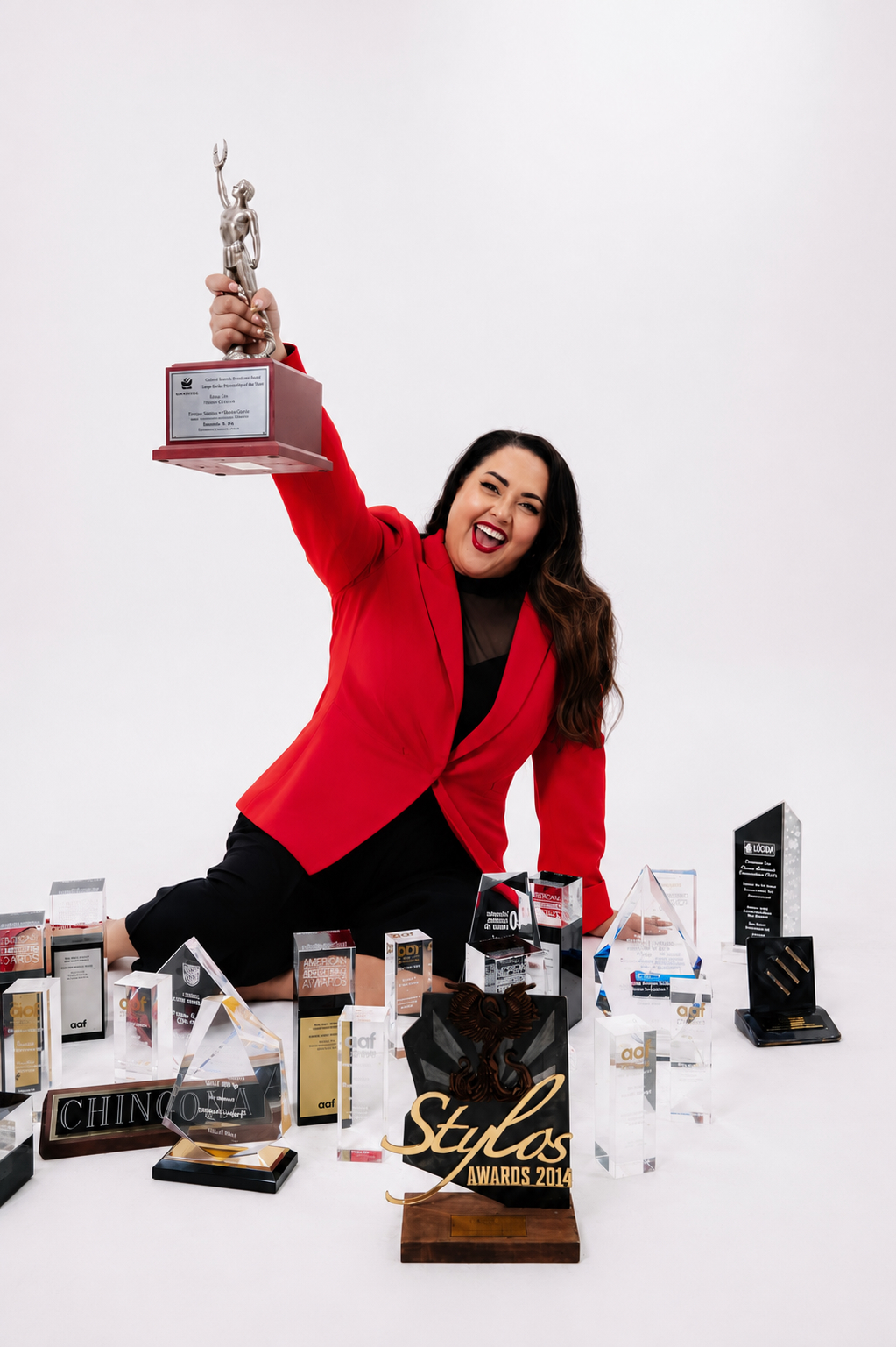 Tania Torres raising an award surrounded by industry trophies